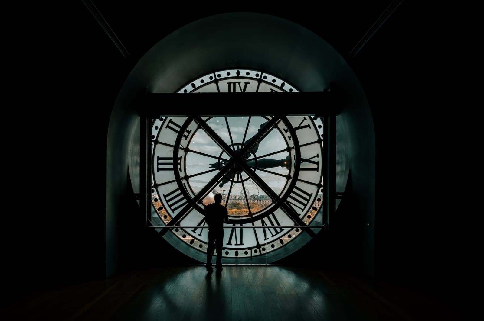 A visitor silhouetted inside the Musée d'Orsay's great clock, with Paris visible through the translucent clock face