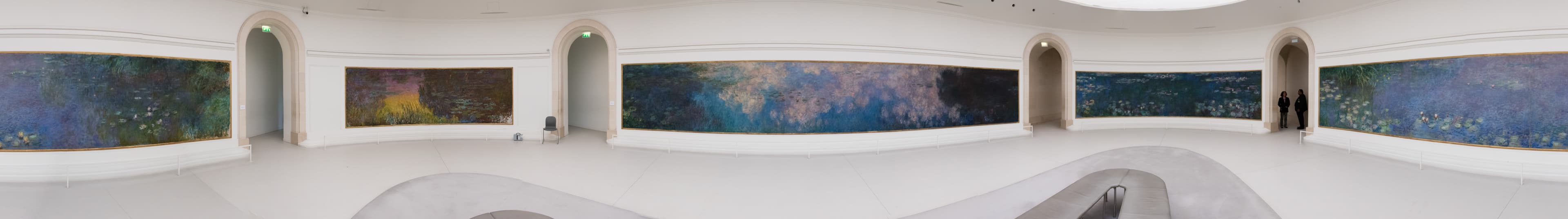 Full panorama of the first oval Water Lilies room: four curved compositions wrapping the walls under diffused light
