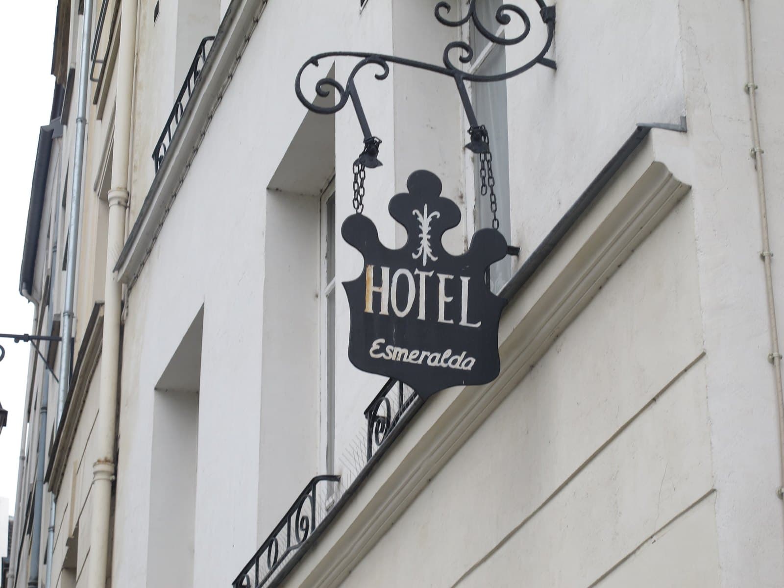 The pale stone exterior and blue sign of Hôtel Esmeralda on rue Saint-Julien-le-Pauvre.