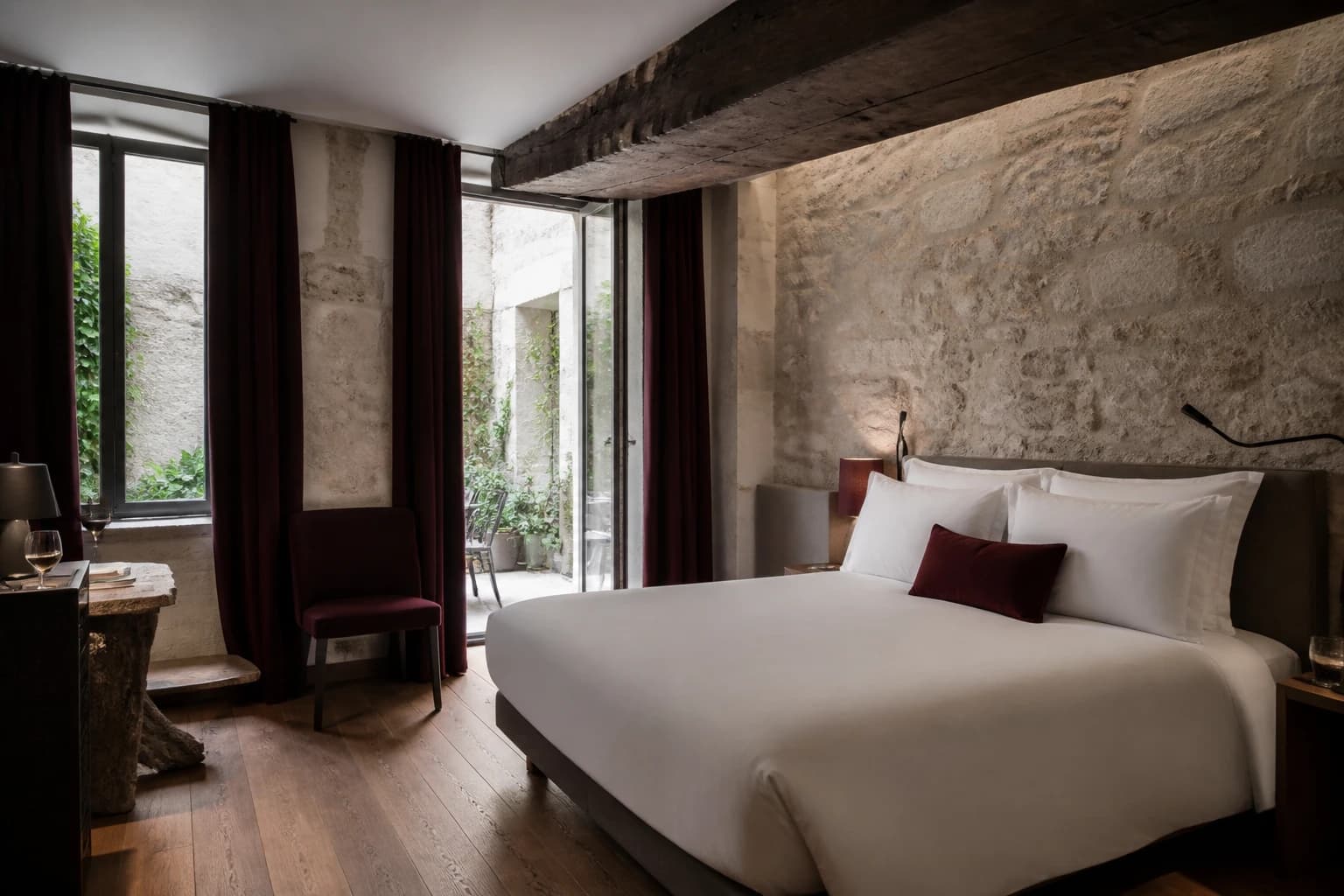 Editorial illustration of a Hôtel Europe Saint-Séverin room with exposed limestone and dark beams, modern white bedding, oak, and burgundy accents.