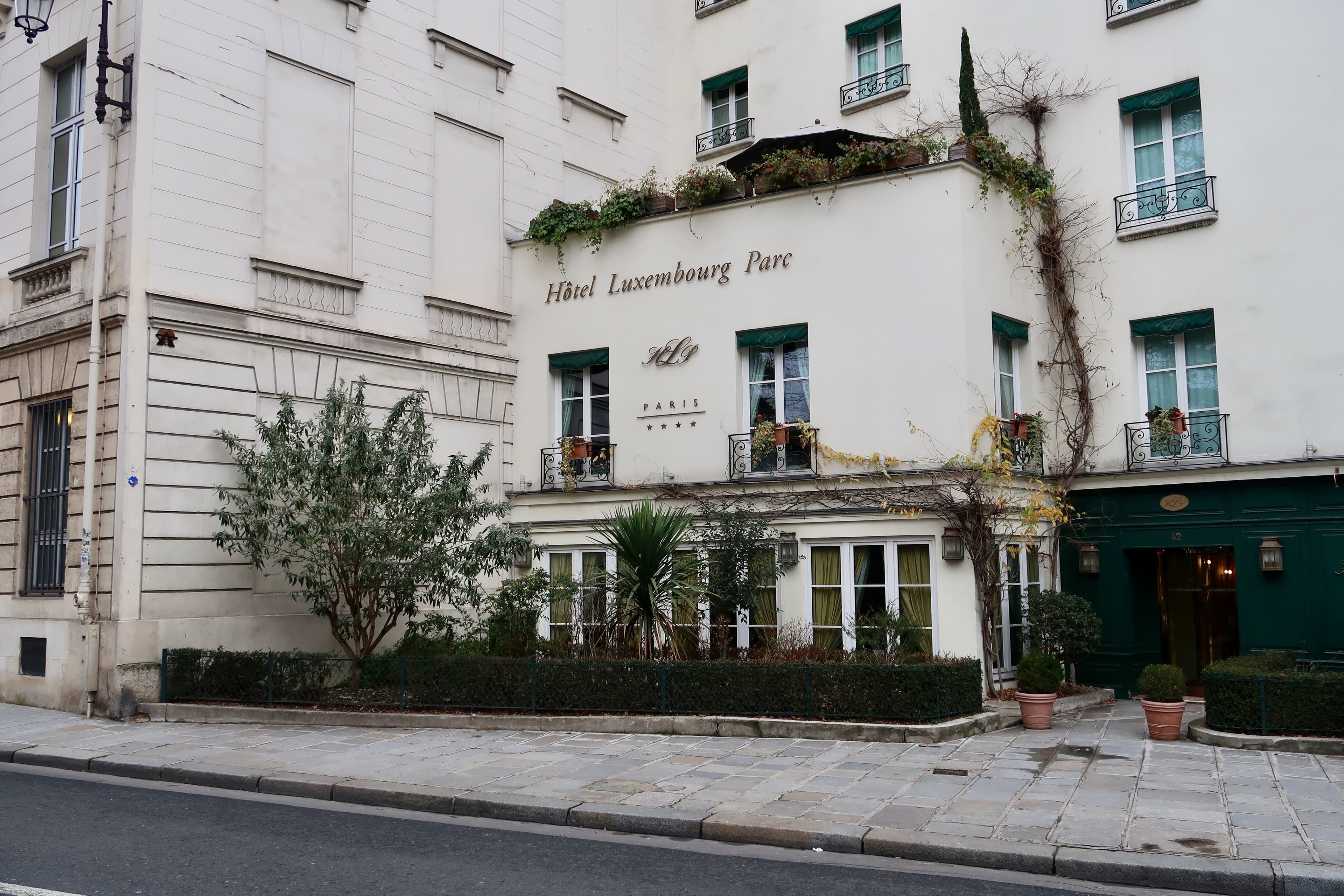Hôtel Luxembourg Parc at 42 rue de Vaugirard, with green shutters and plants outside the entrance, photographed in 2019.
